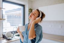 Devojka sluša muziku i pije kafu
