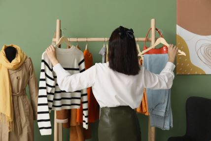 Žena bira odeću za jesenju modnu kapsulu