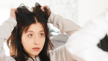 Žena gleda svoju kosu u ogledalu