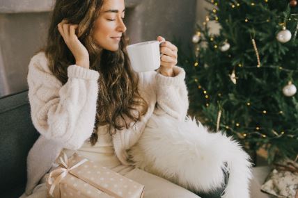 žena pije kafu pored novogodišnje jelke.jpg