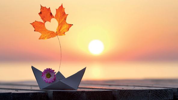 Jesenji list i brod od papira na zalasku sunca