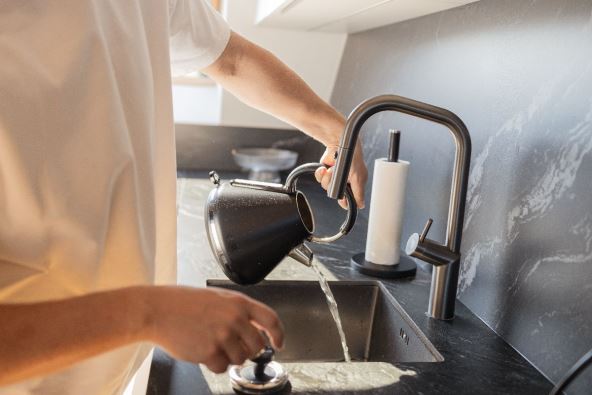 čovek sipa čaj u sudoperu