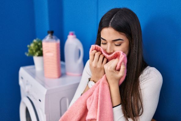 žena miriše džempere posle pranja